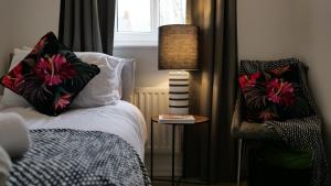 a bedroom with a bed and a lamp and a chair at A Place to Pause, A Place to Belong, Charming Three Bedroom Rainham Retreat with Parking and WiFi in Swindon