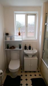 a bathroom with a toilet and a sink and a window at A Place to Pause, A Place to Belong, Charming Three Bedroom Rainham Retreat with Parking and WiFi in Swindon