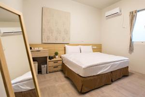 1 dormitorio con cama, escritorio y espejo en Success 66 B&B en Taitung