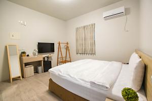 a bedroom with a white bed and a television at Success 66 B&B in Taitung City