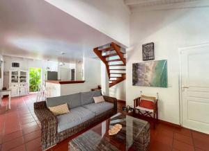 a living room with a couch and a staircase at Villa Douceur & Spa Piscine & Jacuzzi privés - proche plage in Saint-François