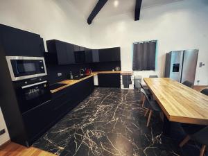 a kitchen with black cabinets and a wooden table at Grande maison moderne 5 chambres in Cherbourg en Cotentin