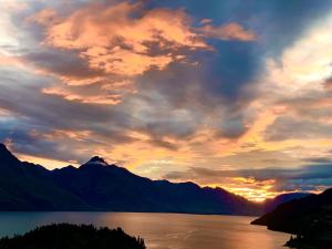 a sunset over a body of water with mountains at The view of Queenstown in Queenstown