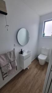a white bathroom with a sink and a mirror at Modern trendy style & comfort in Dunedin +5 photos
