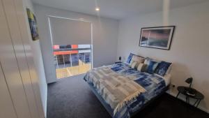 a bedroom with a bed and a large window at Modern trendy style & comfort in Dunedin