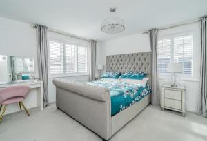 a bedroom with a large bed and a pink chair at 5 Bedroom Detached House in Milton Keynes in Bletchley