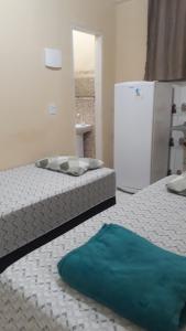 two beds in a room with a refrigerator at Porto apartamento in Porto Seguro