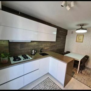 a kitchen with white cabinets and a sink and a table at Ботаника , парк долина роз аеропорт in Chişinău