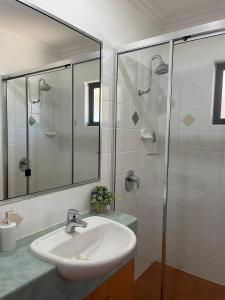 a bathroom with a sink and a glass shower at Pool Side Holiday Home in Agnes Water