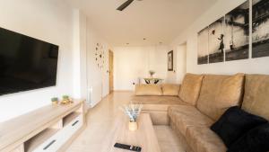 Una sala de estar con un sofá marrón y un televisor de pantalla plana. en H&H Suite Granada Apartament, en Armilla