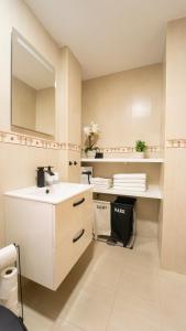 Un baño blanco con lavabo y espejo. en H&H Suite Granada Apartament, en Armilla