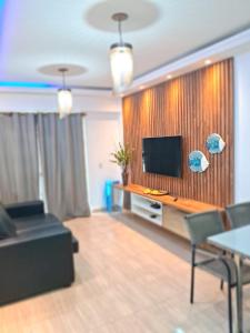 a living room with a couch and a flat screen tv at Apartamento Beach place Cumbuco 100metros Praia in Caucaia