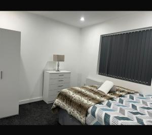 a bedroom with a bed and a dresser and a window at Luton Centrally Located Apartment v close London Luton Airport in Luton