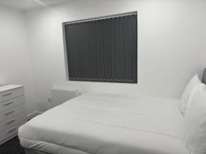 a white bedroom with a bed and a window at Luton Centrally Located Apartment v close London Luton Airport in Luton