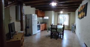 a kitchen with a refrigerator and a table with chairs at CABAÑAS KUME in Potrero de los Funes
