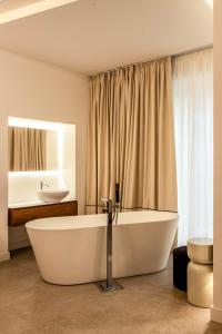 a large white bath tub in a bathroom with a sink at Mamalu - Corso Umberto 35 in Naples