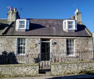 a stone house with two windows and a fence at Atticus Central Guest House in Aberdeen
