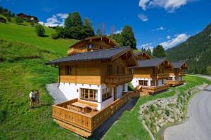 a group of wooden houses on a hill with a road at Tauernchalets in Grossarl