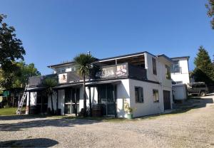 a white building with a palm tree in front of it at Airport Guesthouse in Queenstown