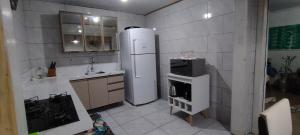 eine kleine Küche mit Kühlschrank und Spüle in der Unterkunft Casa em Tramandaí in Tramandaí