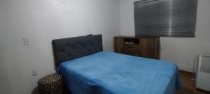 ein Schlafzimmer mit einem Bett mit einer blauen Bettdecke in der Unterkunft Casa em Tramandaí in Tramandaí