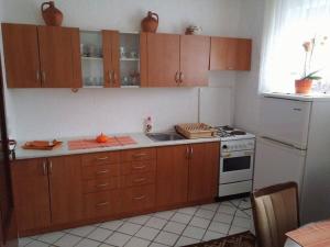 a kitchen with wooden cabinets and a white stove at Apartment Božić in Vrbovsko
