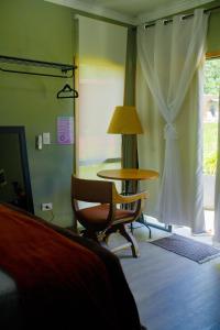 a room with a table and a chair and a lamp at Ambar in São Pedro