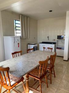 a kitchen with a table and chairs and a refrigerator at apartamento 3 quartos in Rosário do Sul