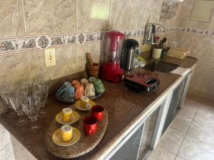 a kitchen counter with plates and cups and a sink at Sítio Montanhas Gerais in Sabará