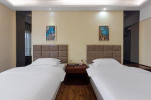 大面镇Home Inn Paibaiyun Hotel Chengdu Longquanyi Normal University Modern Garden Branch的酒店房间里有两张床，铺着白色床单