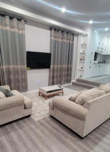 a living room with two couches and a tv at The Royal Haven Herstelling, Georgetown in Nismes