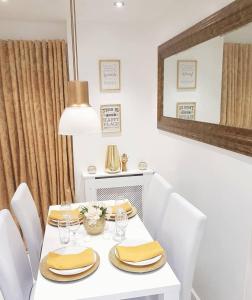 a white dining room table with white chairs and a mirror at Cosy and stylish 3 bedroom house in Middleton +8 photos