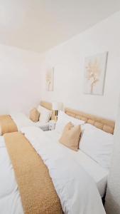 a row of white beds sitting next to each other at Cosy and stylish 3 bedroom house in Middleton