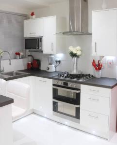 a white kitchen with a stove and a vase of flowers at Cosy and stylish 3 bedroom house in Middleton
