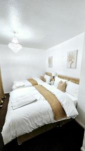 a bedroom with three beds with white sheets and a chandelier at Cosy and stylish 3 bedroom house in Middleton