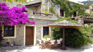 a stone house with a table and an umbrella at Anastasia Luxury Villas in Gavrio