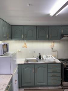 a kitchen with green cabinets and a sink at Aurora's Lighthouse - Caminhos de Santiago in Vila Chã