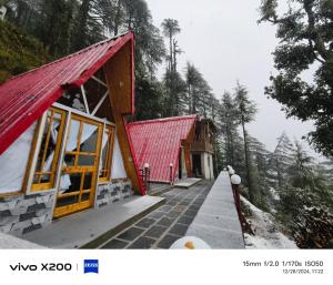 a building with a red roof on a snowy mountain at Eva Cabins in Dalhousie