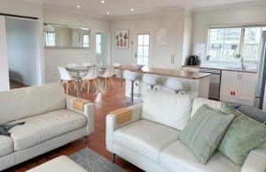 a living room with two white couches and a kitchen at Coastal Sanctuary, Spa, EV friendly, Pet Firendly with Fireplace, wood provided Just 50m to Kilcunda Beach and 100m to the Ocean View Hotel The Sticks and Copper Door Kitchen Accessibility Friendly in Kilcunda