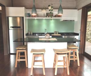 a kitchen with a counter and some wooden stools at Tropical Escape Villa - Comfort & Serenity Await! in Irioa