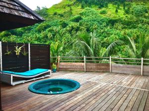 a hot tub on a deck with a chair and a mountain at Tropical Escape Villa - Comfort & Serenity Await! in Irioa