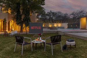 a screen with a netflix sign in a yard at SaffronStays Pristine Manor - 8-BR Udaipur villa with private pool, garden, and event space near Fateh Sagar Lake in Udaipur
