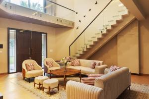 a living room with chairs and a table and stairs at SaffronStays Pristine Manor - 8-BR Udaipur villa with private pool, garden, and event space near Fateh Sagar Lake in Udaipur