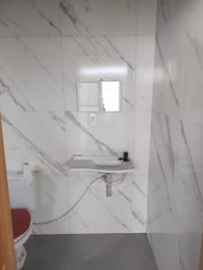 カパン・ダ・カノアにあるSobrado Geminado em Capão Novoの洗面台とトイレを備えた白いバスルーム