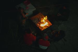 a group of people standing around a fire pit at Zankhrpas A Himalayan Home - Manali in Manāli