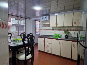 kuchnia z białymi szafkami oraz stołem i krzesłami w obiekcie Habitación baño privado garaje moto, Manizales w mieście Manizales