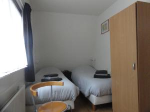 een kleine kamer met 2 bedden en een stoel bij Vakantiewoning Duinoord Domburg in Domburg
