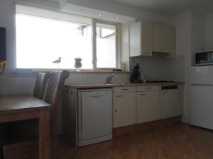 een keuken met witte kasten, een wastafel en een raam bij Vakantiewoning Duinoord Domburg in Domburg