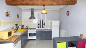 cocina con armarios azules y nevera blanca en Gîte Les Mimosas, en Prugnanes