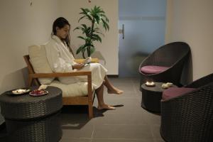 a woman sitting in a chair reading a book at Hotel Mira Sagres in Vila do Bispo